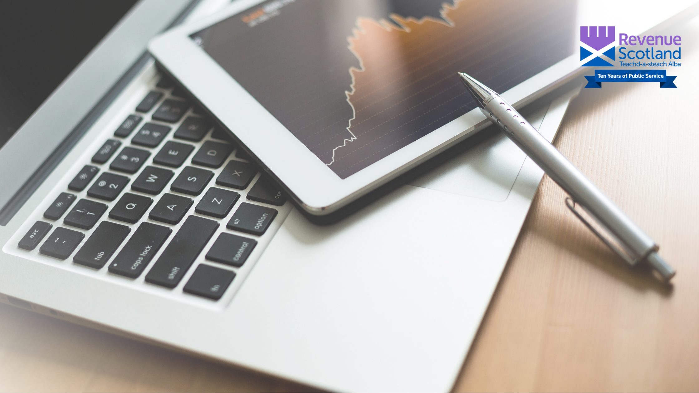 A laptop, tablet and pen on a desk
